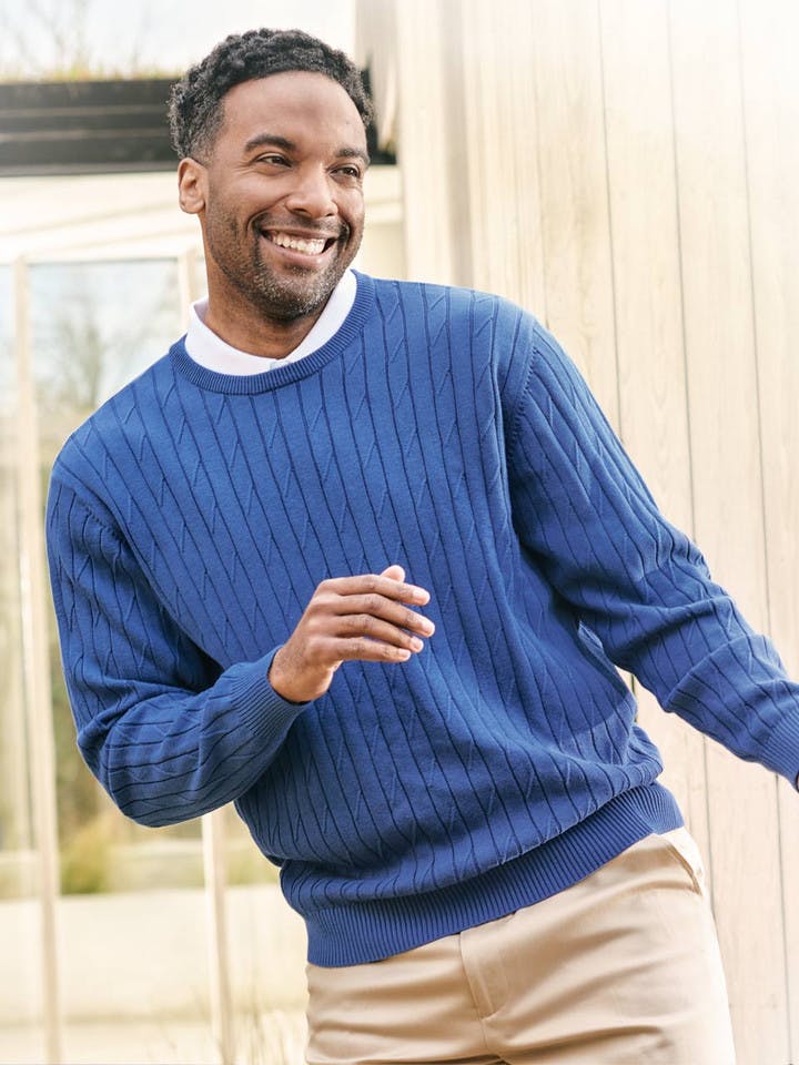 Model wearing blue cotton cable crew neck jumper